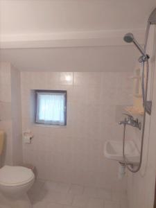 a white bathroom with a toilet and a window at Villa Sofia in Chernomorets