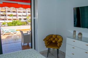 a bedroom with a bed and a television and a chair at PARQUE SANTIAGO I Stunning brand new apt 2 bedroom Playa de las Américas in Playa de las Americas