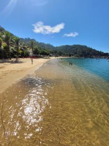 una playa con gente nadando en el agua en Angra dos Reis, Angra Inn, Cantinho perfeito en Angra dos Reis