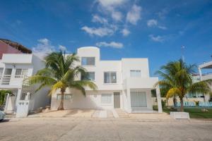 a white house with palm trees in front of it at Beautiful 7BDR Home by Isla Mujeres Ferry in Cancún