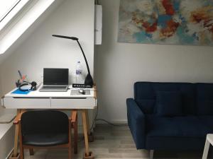 una scrivania con un computer portatile accanto a un divano blu di Studio chez Virginie et Henri a Le Mée-sur-Seine