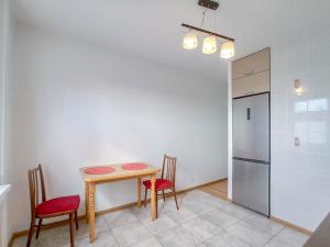 eine Küche mit einem Tisch und Stühlen sowie einem Kühlschrank in der Unterkunft Apartamentai ramioje vietoje in Šiauliai