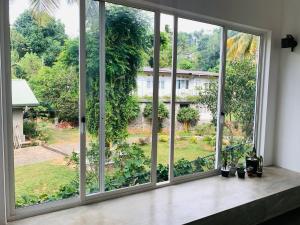 een kamer met grote ramen met uitzicht op een tuin bij Everdew Kandy in Kandy