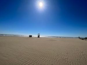 uma praia de areia com o sol no céu em Nido Appartamento em Cavallino-Treporti
