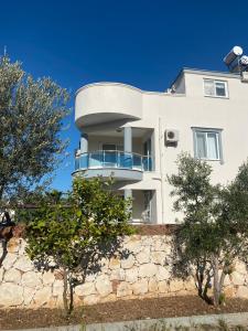a white building with a balcony on top of a stone wall at Three Bed villa, Private Pool in Didim