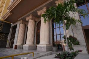 a palm tree in front of a building with columns at Palm Boutique Hotel in Jeddah