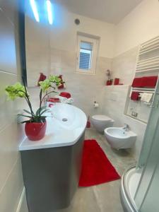 a bathroom with a white sink and a toilet and a red rug at Il Giardino dei Ciliegi in Colico
