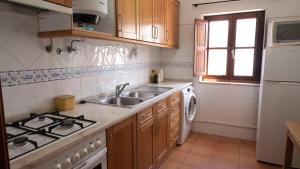 a kitchen with a sink and a stove at Casa BARCA DO SOL in Vila Nova de Milfontes