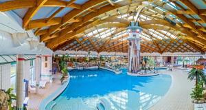 a large swimming pool in a resort with a large ceiling at Hiška Ela 109 in Mostec
