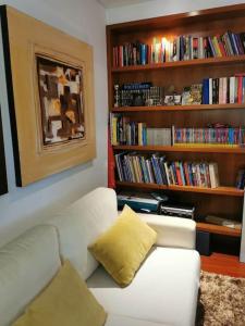 a living room with a white couch and a book shelf at Casa das Camélias in Guimarães