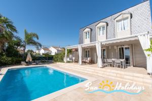 a villa with a swimming pool in front of a house at Villa Oasis in El Vendrell