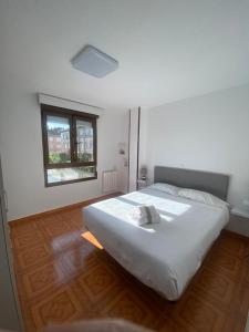1 dormitorio con 1 cama blanca grande y ventana en Piso a 50m de la Playa en Somo con Garaje Privado, en Somo