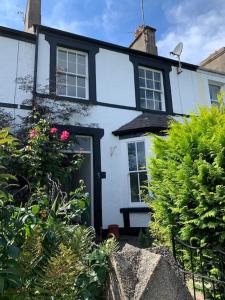 a white house with a black door and some bushes at 3 Newboro Terrace, Conwy in Conwy