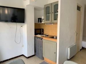 Elle comprend une petite cuisine avec un évier et une télévision murale. dans l'établissement Studio Balaruc-les-Bains, 1 pièce, 2 personnes - FR-1-503-161, à Balaruc-les-Bains