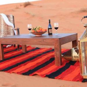 Merzouga heart camp في مرزوقة: طاولة مع كأسين من النبيذ وصحن من الفاكهة