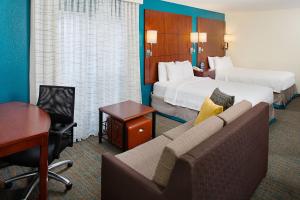 a hotel room with two beds and a couch and a desk at Residence Inn Ontario Airport in Ontario