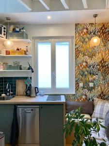 eine Küche mit einem Waschbecken und einem Fenster in einem Zimmer in der Unterkunft Chez Valentine au coeur des Buttes Chaumont et Belleville in Paris