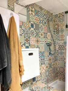 een badkamer met een toilet en een betegelde muur bij Chez Valentine au coeur des Buttes Chaumont et Belleville in Parijs