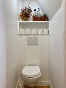 biała łazienka z toaletą i ręcznikami w obiekcie Chez Valentine au coeur des Buttes Chaumont et Belleville w Paryżu