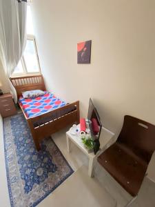 ein kleines Schlafzimmer mit einem Bett und einem Stuhl in der Unterkunft MBZ - Relax Room in Unique Flat in Abu Dhabi