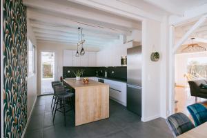 a kitchen with black and white cabinets and a wooden island at Maison Le Basta in Bégaar