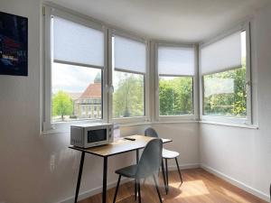 a room with a desk with a computer and three windows at Zentral gelegene Studios I home2share in Osnabrück