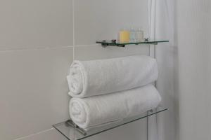 una pila di asciugamani su una mensola in vetro in bagno di Hotel Viaggio 617 a Bogotá
