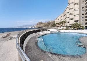 una piscina junto a un edificio y al océano en Tabaiba Sunset sea Views, en Santa Cruz de Tenerife