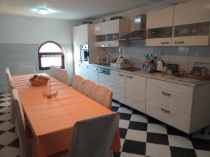 a kitchen with a long table with chairs and a kitchen at Vila sumska idila in Banja Koviljača