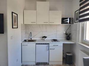 a white kitchen with white cabinets and a sink at A Comfortable and Modern Newly Renovated Apartment in Mannheim