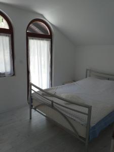 a bedroom with a bed and two windows at Vila sumska idila in Banja Koviljača