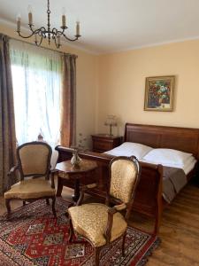 een slaapkamer met een bed en een tafel en stoelen bij Dwór na Wrzosowisku in Krzywe