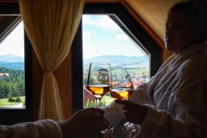 Una donna che porta due bicchieri di vino davanti a una finestra di Vila Breg Zlatibor a Zlatibor