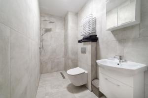 a white bathroom with a toilet and a sink at WODA I WIATR PL Wiatrakowa 26 Jastrzębia Góra in Jastrzębia Góra +32 photos