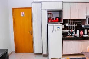 a kitchen with a refrigerator and a orange door at Um plus na sua acomodação - LOFT FELAU in Cuiabá