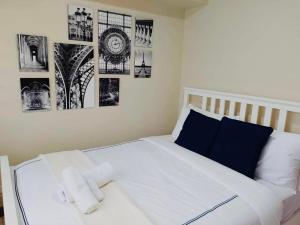 een slaapkamer met een wit bed met foto's aan de muur bij Larue cozy room in Solemare Parksuites Paranaque in Manilla