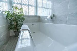 La salle de bains est pourvue d'une baignoire blanche et d'une plante. dans l'établissement WV Top Flat Bowness Center, à Bowness-on-Windermere