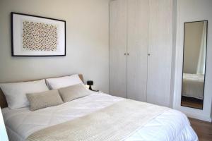 a bedroom with a white bed and a mirror at KAPA Central Apartment in Kalamata