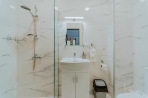 bagno bianco con lavandino e doccia di Lemy Lux Apartments a Velingrad