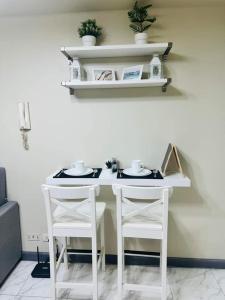 een witte tafel met twee witte stoelen en planken bij Larue cozy room in Solemare Parksuites Paranaque in Manilla