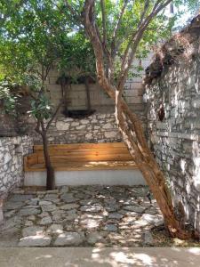 a wooden bench in a stone wall with a tree at Urla bir nefes taş ev in Urla