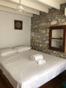 - un lit blanc dans une chambre dotée d'un mur en pierre dans l'établissement Urla bir nefes taş ev, à Urla
