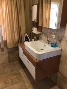 La salle de bains est pourvue d'un lavabo blanc et d'un miroir. dans l'établissement Urla bir nefes taş ev, à Urla