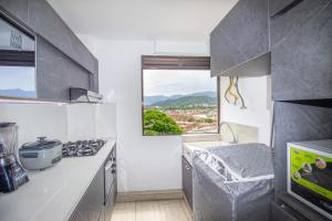 a kitchen with a stove top oven next to a window at Excelente apartamento cerca a parques turísticos in Medellín