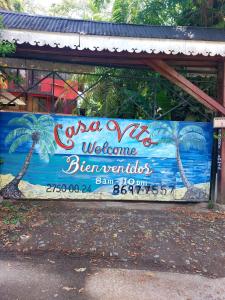 a sign on a building with palm trees on it at Hotel Casa Vito Beachfront in Puerto Viejo