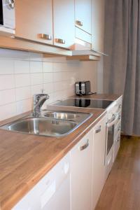een keuken met een roestvrijstalen wastafel en witte kasten bij MM City Apartment Ratina Close to Arena in Tampere