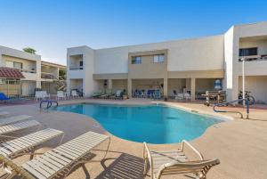 a swimming pool with lounge chairs in front of a building at Sunbeam Condo in Scottsdale