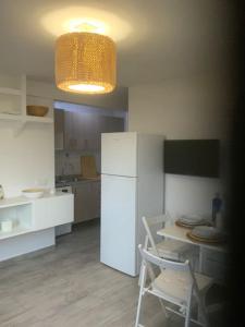 eine Küche mit einem weißen Kühlschrank sowie einem Tisch und Stühlen in der Unterkunft Es Pujols isla de la Calma in Es Pujols
