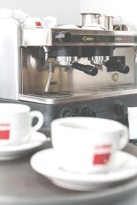 eine Kaffeemaschine mit zwei Tassen auf der Theke in der Unterkunft Garni Hotel MB in Budva