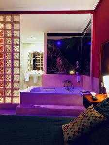 Motel Montecarlo في لوغو: حمام كبير مع حوض استحمام مع إضاءة أرجوانية